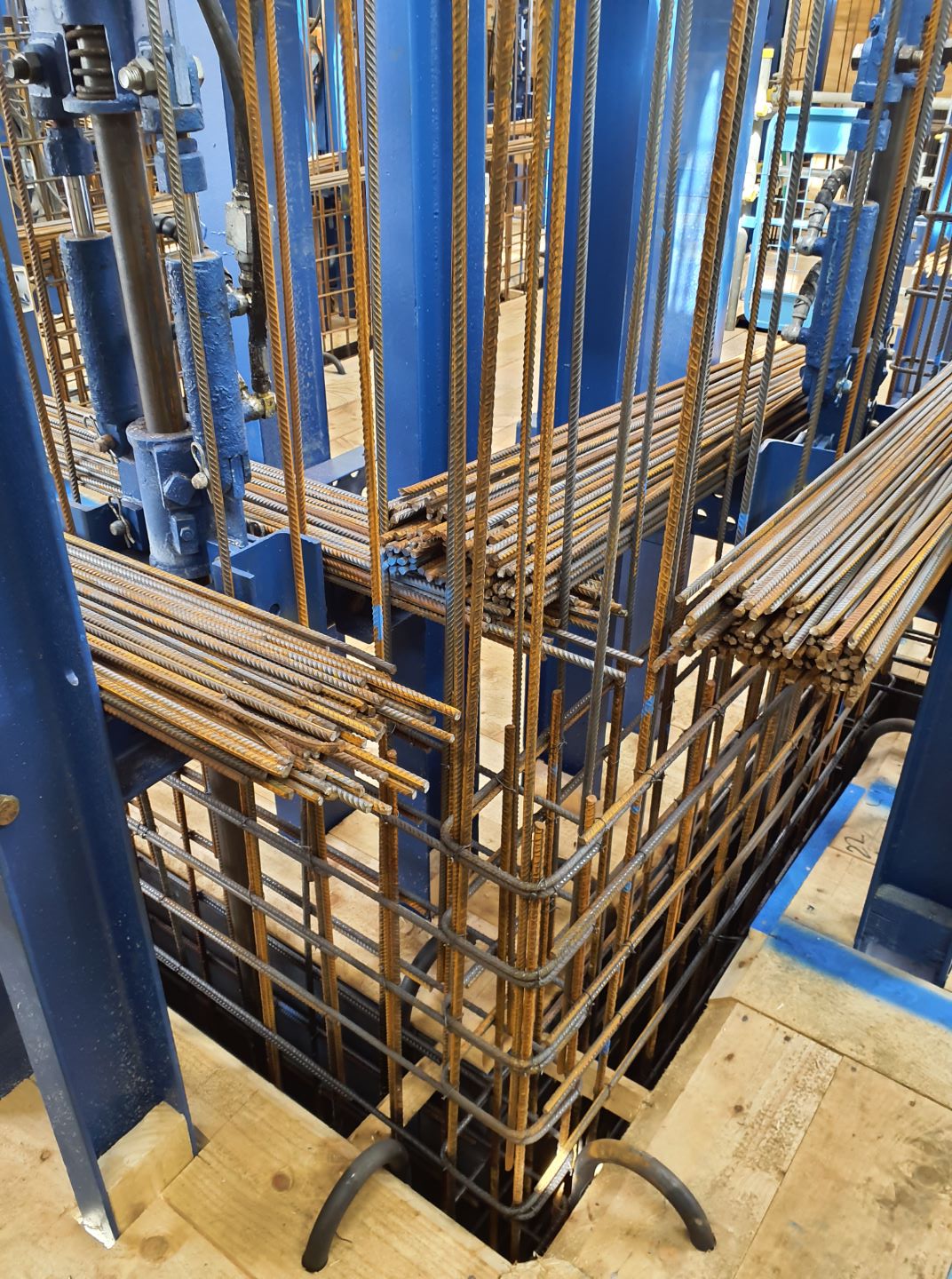 Interior of a building being built with blue beams and thick metal wire